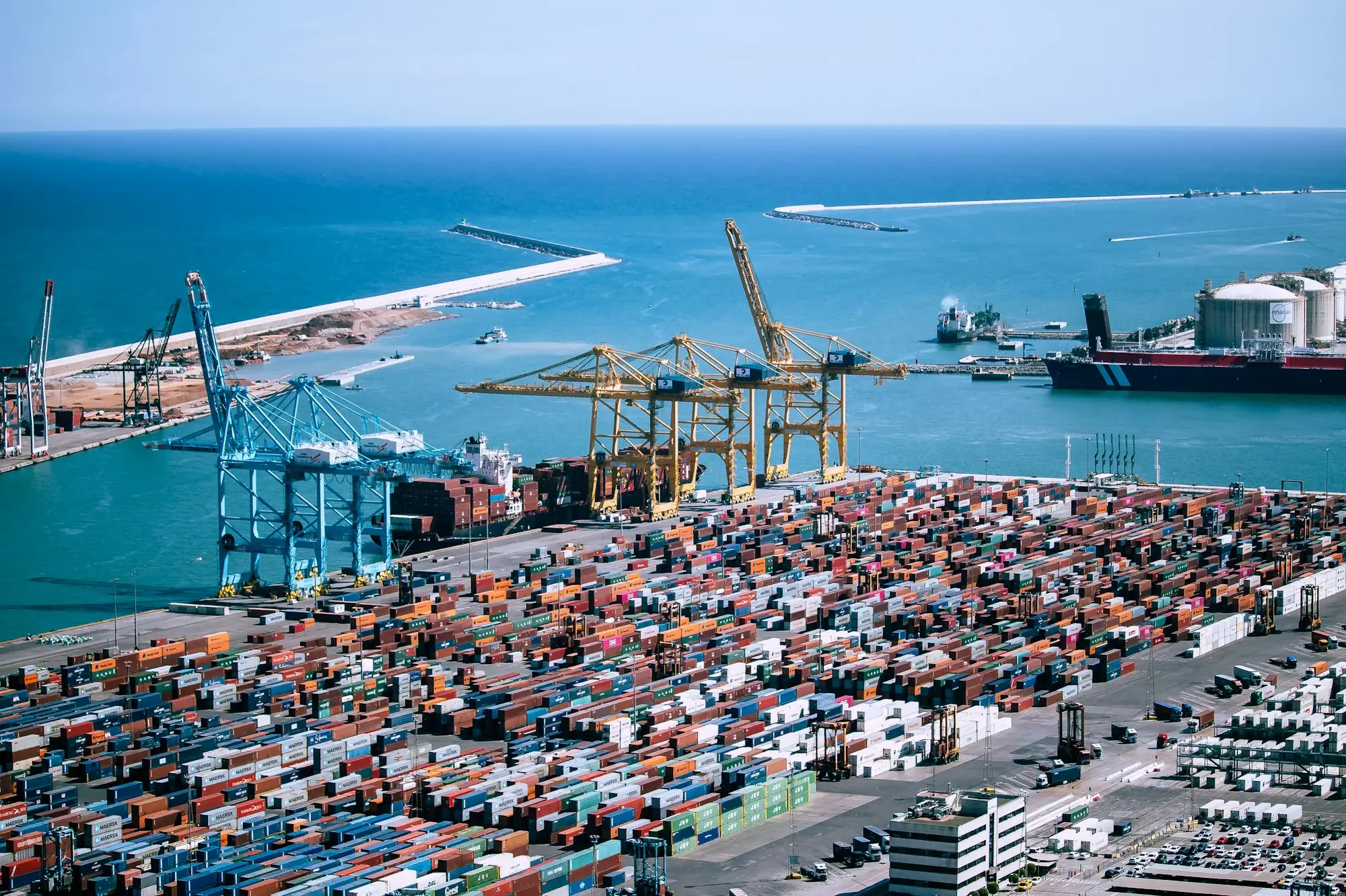 Aerial view of a busy container terminal with stacked shipping containers and gantry cranes, where imported goods wait for duty and GST to be paid before release