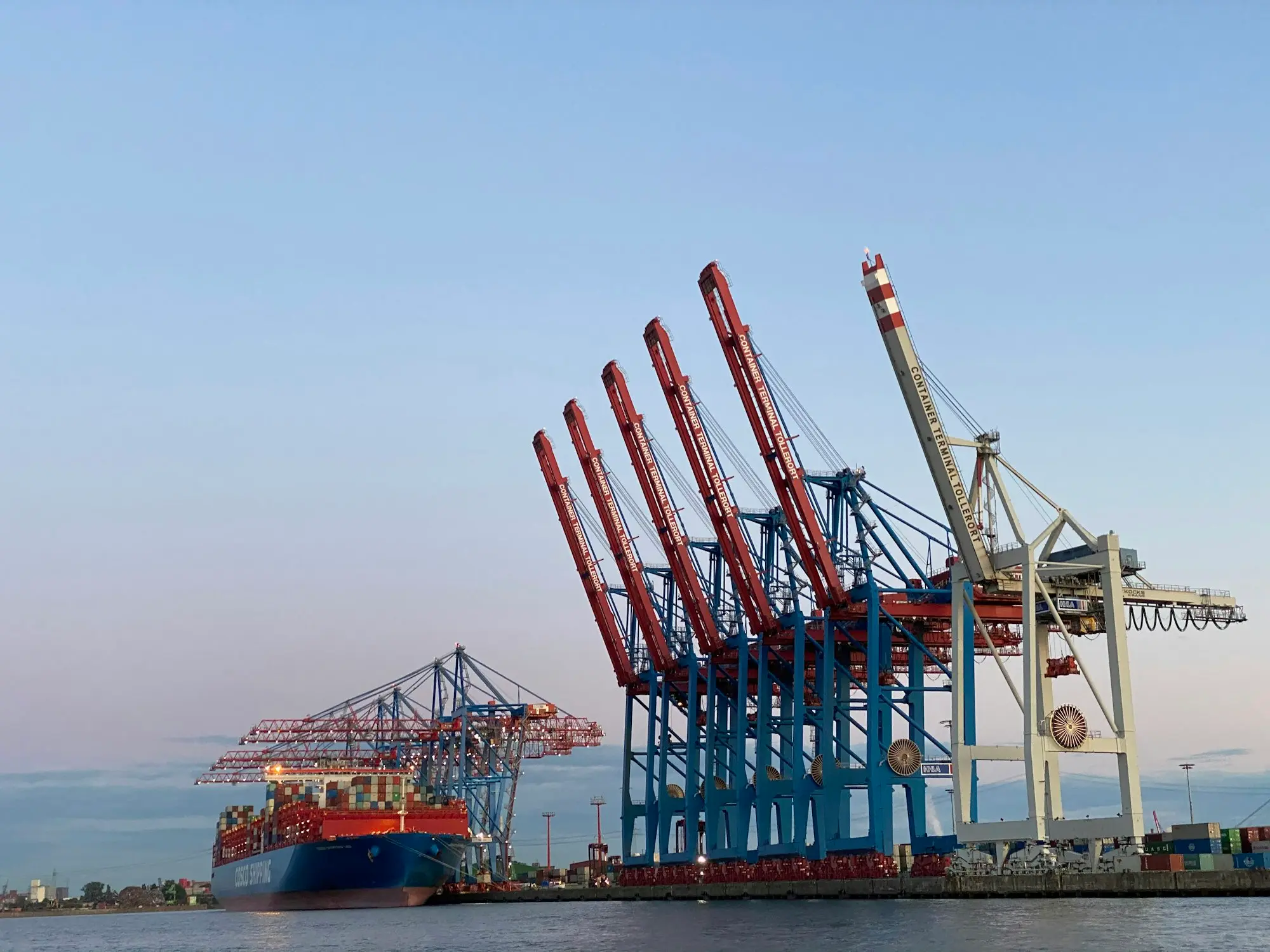Container ship berthed beside gantry cranes at a container terminal, loading full container loads for import